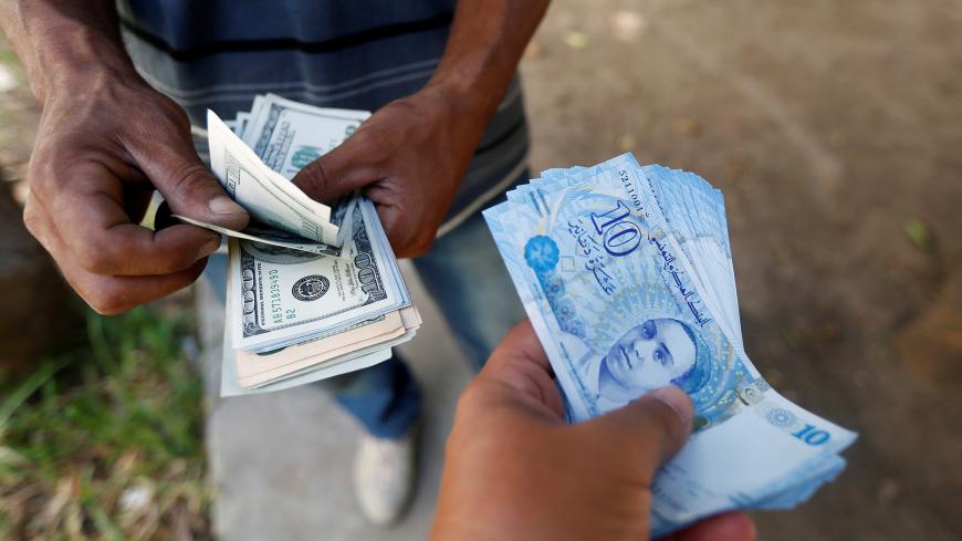 A man buys dollars  from a money changer on the black market in the capital Tunis, Tunisia August 24, 2017. REUTERS/Zoubeir Souissi - RC1CA2FB0820