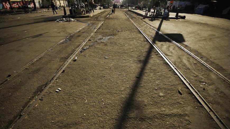 People walk on a railway track as Egyptian army troops are deployed outside the of the presidential palace in Cairo on December 12, 2012, one day after thousands of Egyptians protested against the upcoming referendum on the new draft constitution. Egypt's powerful army has called for President Mohamed Morsi and the secular opposition to meet later in the day to stop a crisis over an imminent constitutional referendum from tearing the country apart. AFP PHOTO/GIANLUIGI GUERCIA        (Photo credit should rea