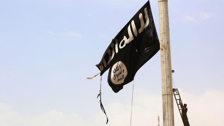A member of the US-backed Syrian Democratic Forces (SDF), made up of an alliance of Arab and Kurdish fighters, removes an Islamic State group flag in the town of Tabqa, about 55 kilometres (35 miles) west of Raqa city, on April 30, 2017, as they advance in their battle for the group's de facto capital. - US-backed fighters have captured 80 percent of Syria's Tabqa from the Islamic State group, a monitor said on May 1, a week after they first entered the town. (Photo by DELIL SOULEIMAN / AFP) (Photo c