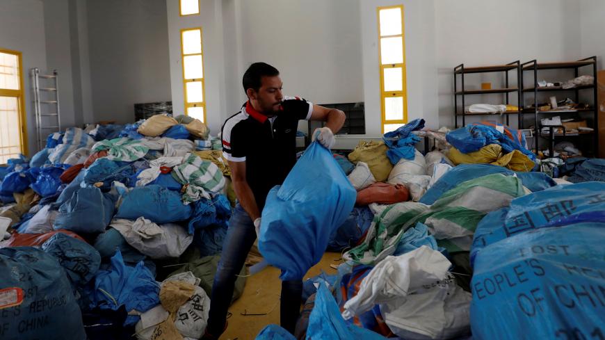 A Palestinian worker carries a bag containing items sent by mail eight years ago, after Israel allowed the letters and goods into the West Bank from Jordan, where they were being held, Jericho, in the occupied West Bank August 19, 2018. REUTERS/Mohamad Torokman - RC17D7B6DB90