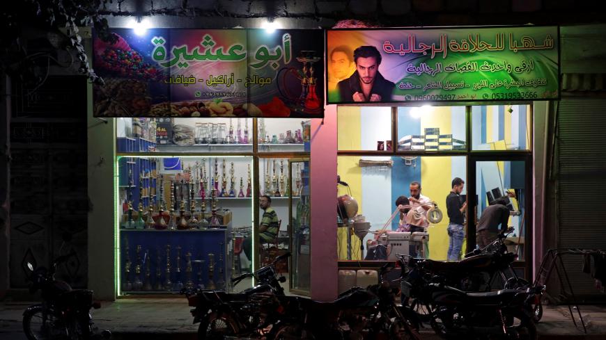 A barber works inside his shop on the southern outskirts of the Syrian city of al-Bab, Syria September 15, 2017. Picture taken September 15, 2017.  REUTERS/Khalil Ashawi - RC11D33413A0