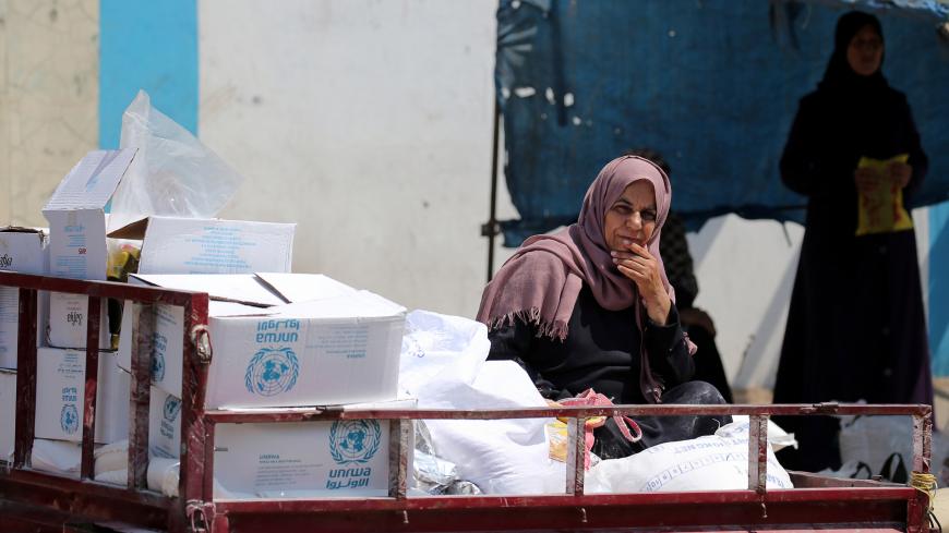 A Palestinian woman sits in a motorised vehicle loaded with aid, outside a distribution center run by the United Nations Relief and Works Agency (UNRWA), in Khan Younis in the southern Gaza Strip September 4, 2018. REUTERS/Ibraheem Abu Mustafa - RC1A87FA4580
