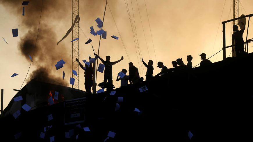 Protesters throw documents as they stand on concrete blast walls during an anti-government protest near the burnt building of the government office in Basra, Iraq September 7, 2018. REUTERS/Alaa al-Marjani - RC1B9ABCCF30