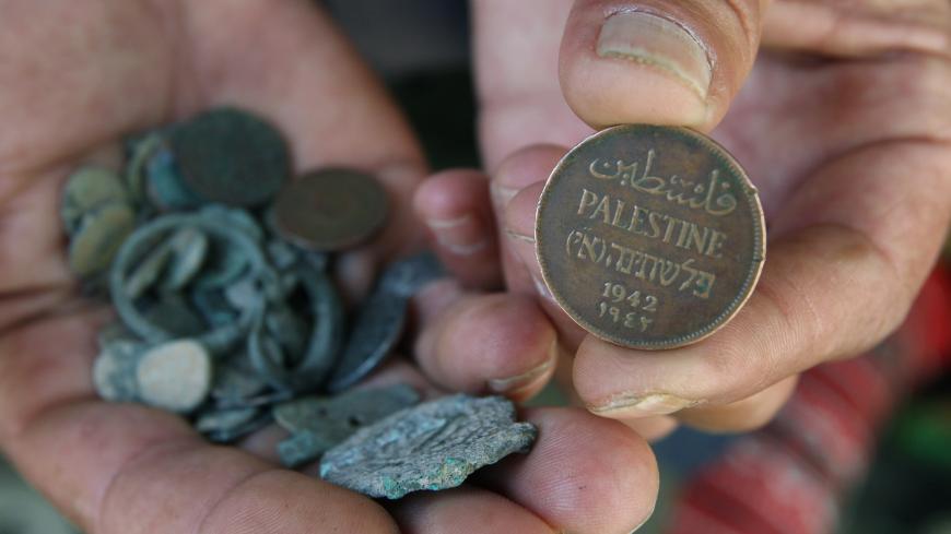 A Palestinian man displays an old Palestinian coin in his shop in the West Bank city of Hebron June 8, 2008. The Palestinian Authority has delayed paying its workers this month after Israel withheld tax funds in anger over Palestinian attempts to block upgraded European Union-Israeli ties, officials said on Sunday. REUTERS/Nayef Hashlamoun (WEST BANK) - GM1E469047K01