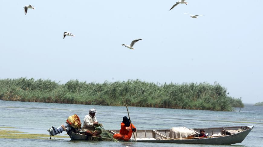 An Iraqi fisherman pulls in his nets as his wife helps in their dug-out on the al-Huwaiza marshes northern Amara, 420 km south of Baghdad on June 13, 2011, considered to be the demarcation line with neighbouring Iran and which were drained by the regime of the late Iraqi leader Saddam Hussein during the Iraqi-Iranian war. Following the collapse of the previous regime, and the entrance of the US-led forces into Iraq in 2003, the water source was opened  with  fifty percent of the marsh land flooded allowing 