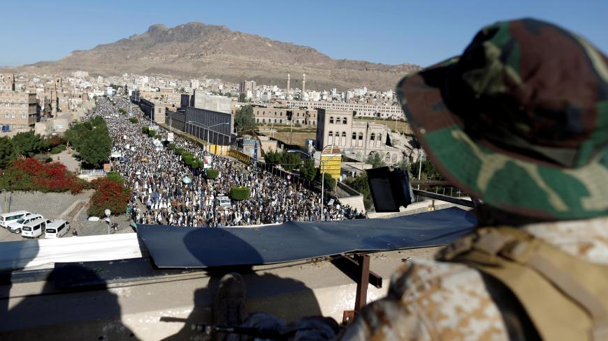 A Houthi militant sits guard on the roof of a building overlooking fellow Houthis rallying to denounce the rapid devaluation of the Yemeni Rial in Sanaa, Yemen October 5, 2018. REUTERS/Khaled Abdullah - RC149994CBB0