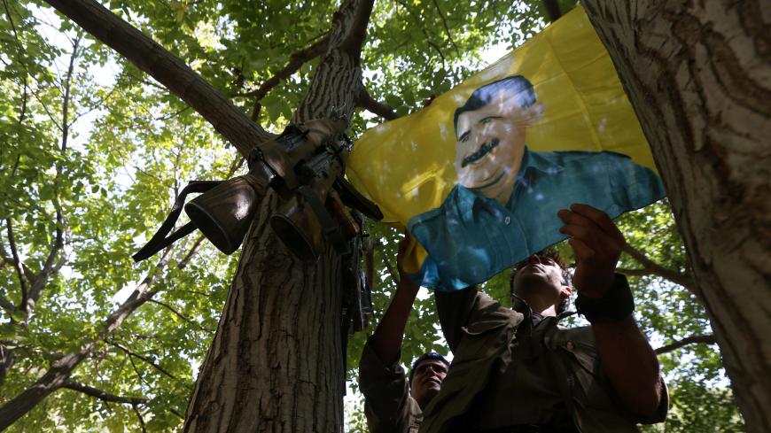 A member of the anti-Iranian group, Kurdistan Free Life Party (PJAK), hangs up a flag of jailed Kurdistan Workers' Party (PKK) leader, Abdullah Ocalan, at their base deep on the Iraq-Iran border of northern Iraq's Kurdish autonomous region, on August 28, 2017. / AFP PHOTO / SAFIN HAMED (Photo credit should read SAFIN HAMED/AFP/Getty Images)
