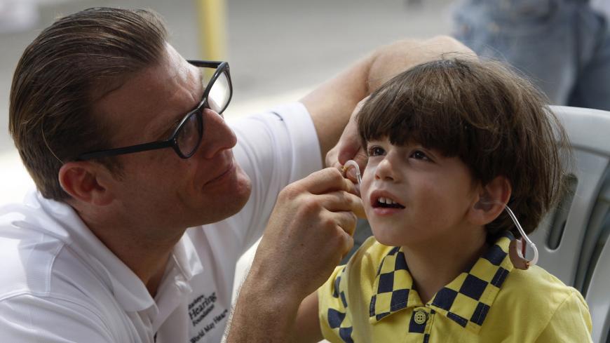 A technician adjusts a hearing aid for a Palestinian boy during an event held by Starkey Hearing Foundation together with other Israeli and non-governmental organisations in the West bank town of Tulkarm May 25, 2011. Hearing aids with custom made ear moulds, developed and donated by Starkey Hearing Foundation, were distributed to more than 1000 Palestinians on Wednesday. REUTERS/Abed Omar Qusini (WEST BANK - Tags: HEALTH SOCIETY) - GM1E75P1SQ101
