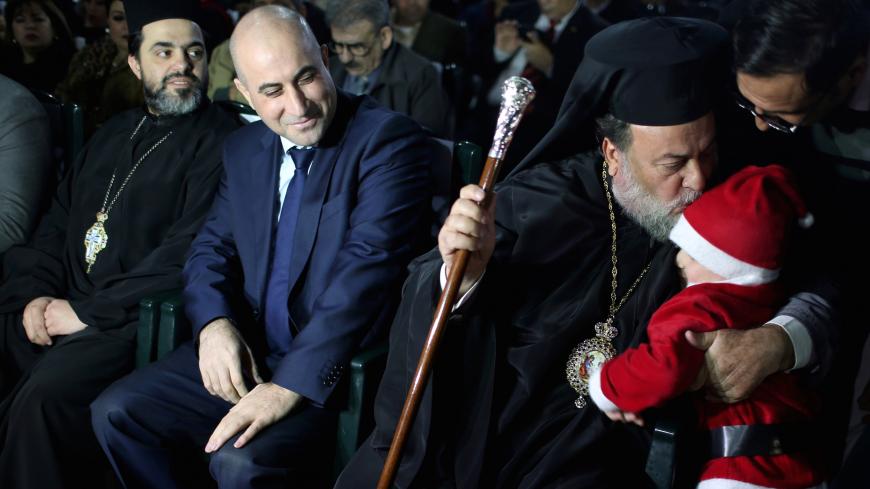 Greek Orthodox Archbishop Alexios kisses a Palestinian child dressed up as Santa Claus during a Christmas tree lighting ceremony in Gaza City December 22, 2018. Picture taken December 22, 2018. REUTERS/Ibraheem Abu Mustafa - RC15B4F1FD50