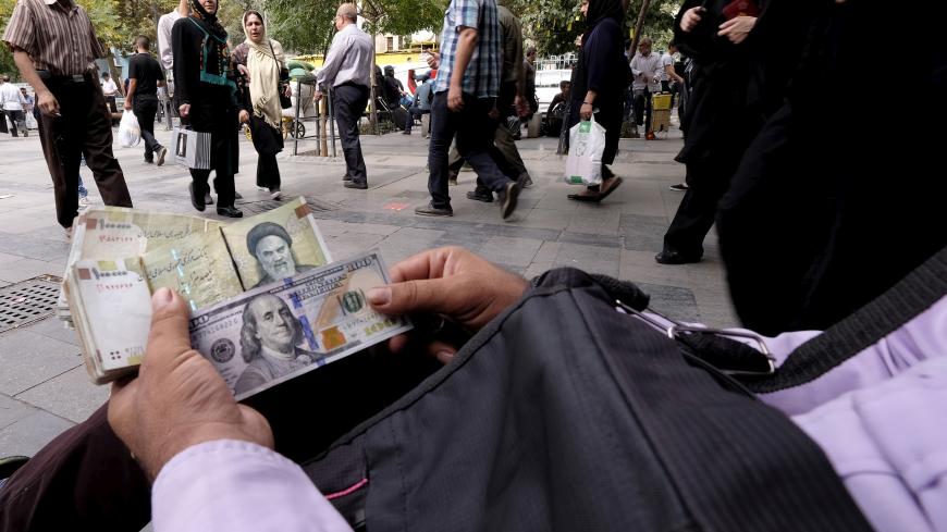 A money changer displays U.S. and Iranian banknotes at the Grand Bazaar in central Tehran October 7, 2015. To match Insight IRAN-BANKING/  REUTERS/Raheb Homavandi/TIMA/File Photo ATTENTION EDITORS - THIS IMAGE WAS PROVIDED BY A THIRD PARTY. EDITORIAL USE ONLY. - S1BETSJMVNAC