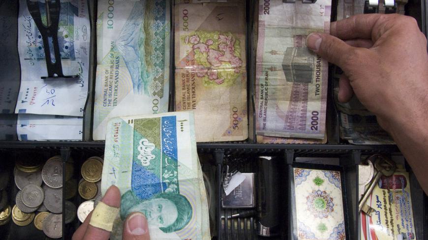 A storekeeper places money in the drawer of the cash register at his shop in Tehran May 4, 2008. With Western banks cutting ties with the Islamic Republic, it is becoming more and more difficult to transfer funds to the country of 70 million people. Tehran's increasing financial isolation is forcing some to bring in money by hand in thick wads of $100 bills on the plane from Dubai, the Gulf's financial centre, or elsewhere. REUTERS/Morteza Nikoubazl (IRAN) - GM1E4580O5Y01