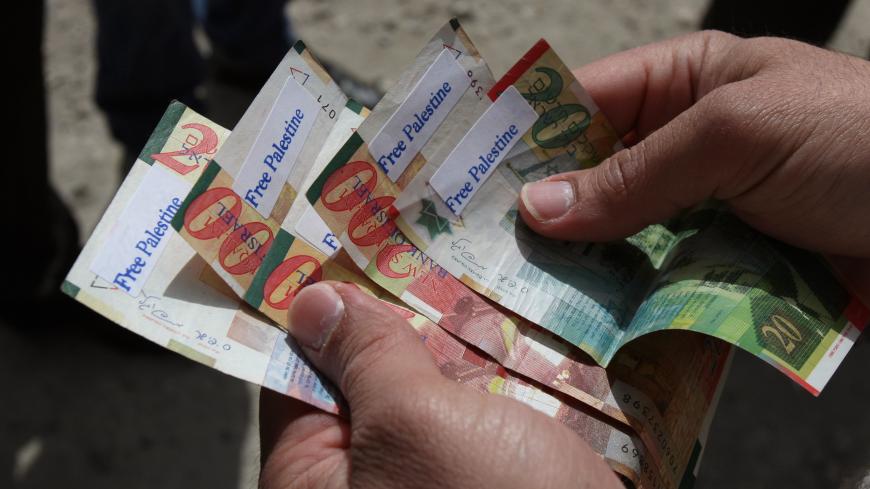 A Palestinian man holds News Israeli Shekels' bills marked with stickers reading "Free Palestine" on March 7, 2011 in the West Bank city of Ramallah, as part of a campaign aimed to peacefully express opposition to Israel's occupation. Young Palestinian activists have found a new medium to protest Israeli occupation: scrawling anti-occupation slogans on the currency they share with the Jewish state. AFP PHOTO/ABBAS MOMANI (Photo credit should read ABBAS MOMANI/AFP/Getty Images)