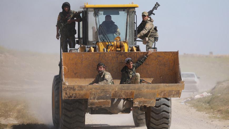 Fighters from the Syrian Democratic Forces (SDF) sit in the bucket of an excavator in the village of Baghouz, Deir Al Zor province, Syria March 20, 2019. Picture taken March 20, 2019. REUTERS/Rodi Said - RC115D5A9480