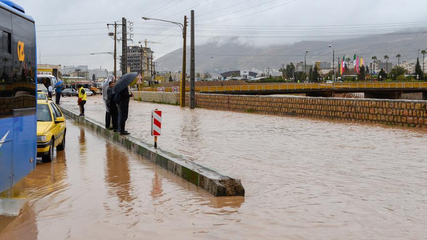People stand near a flooded street after a flash flooding in Shiraz, Iran, March 26, 2019. Tasnim News Agency/via REUTERS ATTENTION EDITORS - THIS PICTURE WAS PROVIDED BY A THIRD PARTY - RC1E3933B310
