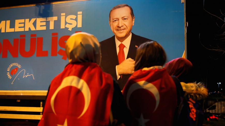 Supporters of AK Party stand in front of a billboard picturing Turkish President Tayyip Erdogan, in Istanbul, Turkey March 31, 2019. REUTERS/Kemal Aslan - RC17147821E0