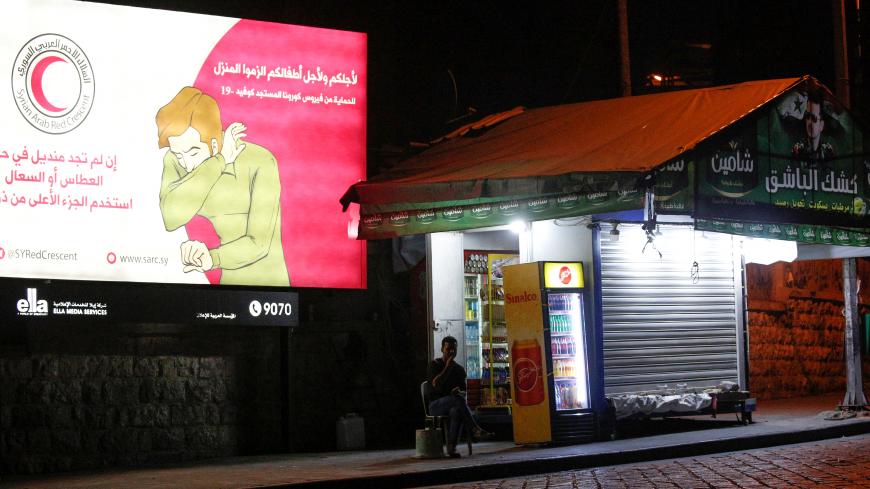 A man sits near a coronavirus awareness billboard, during a lockdown to prevent the spread of coronavirus disease (COVID-19), in Damascus, Syria, April 4, 2020. Picture taken April 4, 2020. REUTERS/Omar Sanadiki - RC2YXF91PSOD