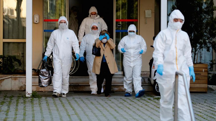 Paramedics escort a woman as she walks toward an ambulance during a two-day curfew which was imposed to prevent the spread of the coronavirus disease (COVID-19), in Istanbul, Turkey, April 12, 2020. REUTERS/Umit Bektas - RC263G9BX0NW