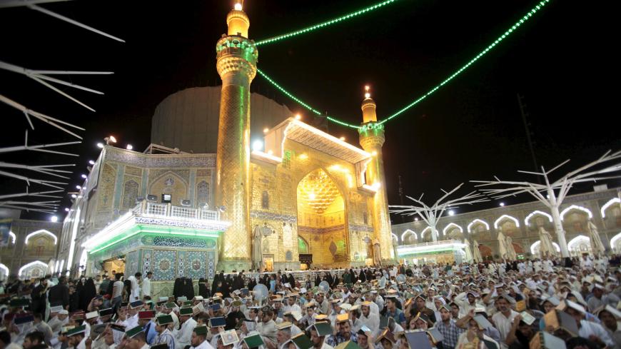 Shi'ite worshippers place copies of the Koran on their heads during Ramadan at the Imam Ali Shrine, Najaf, Iraq July 10, 2015. REUTERS/Alaa Al-Marjani
 - GF10000159772