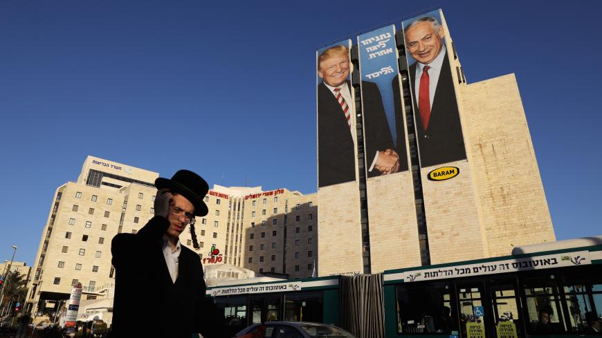 A man walks past a Likud election campaign billboard, depicting U.S. President Donald Trump shaking hands with Israeli Prime Minister Benjamin Netanyahu, in Jerusalem February 4, 2019. REUTERS/Ammar Awad - RC1275660830
