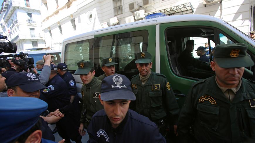 Media and police surround a convoy of police vehicles as businessmen suspected of corruption are driven to court in Algiers, Algeria April 23, 2019. REUTERS/Ramzi Boudina - RC1E854AE410