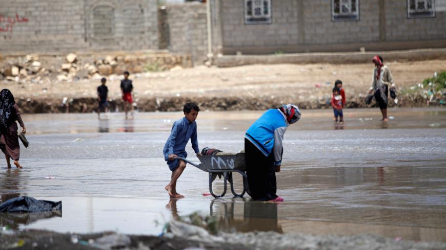 People carry their belongings washed by rain water after the heavy rain in Sanaa, Yemen April 17, 2020. REUTERS/Mohamed al-Sayaghi - RC2B6G94NE9H