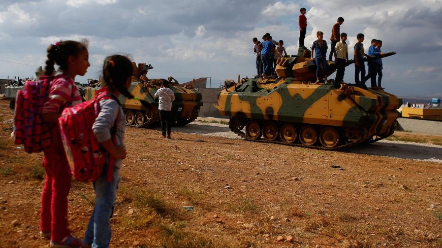 Boys stand on top of a Turkish Armed Forces vehicle, as a military convoy pass by their village on the Turkish-Syrian border line in Reyhanli, Hatay province, Turkey, October 11, 2017. REUTERS/Osman Orsal - RC161DB96200