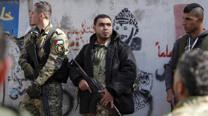Armed gunmen attend the funeral of Fathi Zaydan, a Fatah official responsible for the Palestinian camp of Mieh Mieh, after an explosion that killed him yesterday, during his funeral in Mieh Mieh Palestinian refugee camp, near the port-city of Sidon, Lebanon, April 13, 2016. The wall shows a graffiti of late Palestinian leader Yasser Arafat. REUTERS/Ali Hashisho - GF10000381452