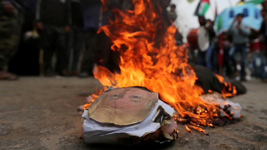 Palestinian demonstrators burn an effigy depicting U.S. President Donald Trump during a protest against U.S aid cuts, outside the United Nations' offices in the southern Gaza Strip February 11, 2018. REUTERS/Ibraheem Abu Mustafa     TPX IMAGES OF THE DAY - RC1D5F27F630