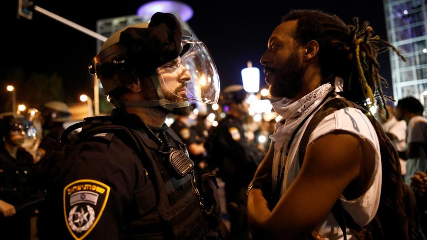 A protester stands opposite to a policeman during a protest for the death of 18-year old Solomon Tekah of Ethiopian descent, after he was shot by police, in Tel Aviv, Israel July 2, 2019. REUTERS/ Corinna Kern - RC132641D330