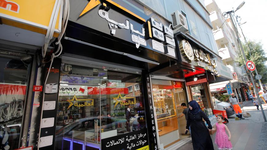 People walk past by a Syrian electronics shop in Istanbul's Kucukcekmece district, Turkey, July 5, 2019. Picture taken July 5, 2019. REUTERS/Kemal Aslan - RC16F16D3FB0