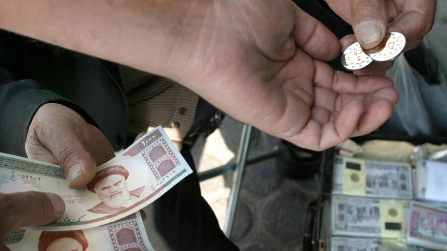 An Iranian man buys new 500 rial coins from a currency trader in Tehran October 31, 2004. Iran has introduced the new coins to eliminate the cost of printing paper money. (8670Rls=1USD) REUTERS/Morteza Nikoubazl  CJF/WS - RP5DRIAPWVAA