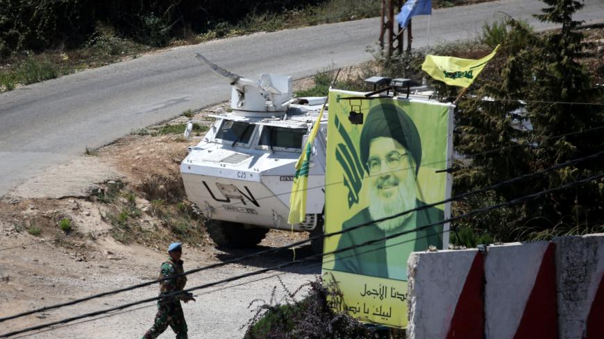 A U.N peacekeepers of the United Nations Interim Force in Lebanon (UNIFIL) walks near a poster depicting Lebanon's Hezbollah leader Sayyed Hassan Nasrallah in Adaisseh, Lebanon August 26, 2019. REUTERS/Ali Hashisho - RC187080F790