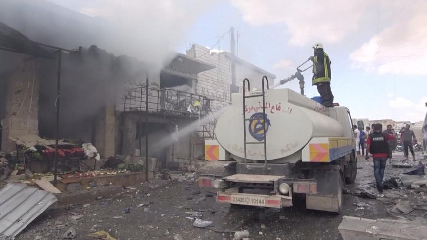 A member of a fire crew sprays water onto a damaged building in a market after an airstrike in this screen grab taken from a social media video said to be taken in Idlib, Syria on July 16, 2019. Picture taken July 16, 2019. White Helmets/social media via REUTERS THIS IMAGE HAS BEEN SUPPLIED BY A THIRD PARTY. - RC1BB344D580