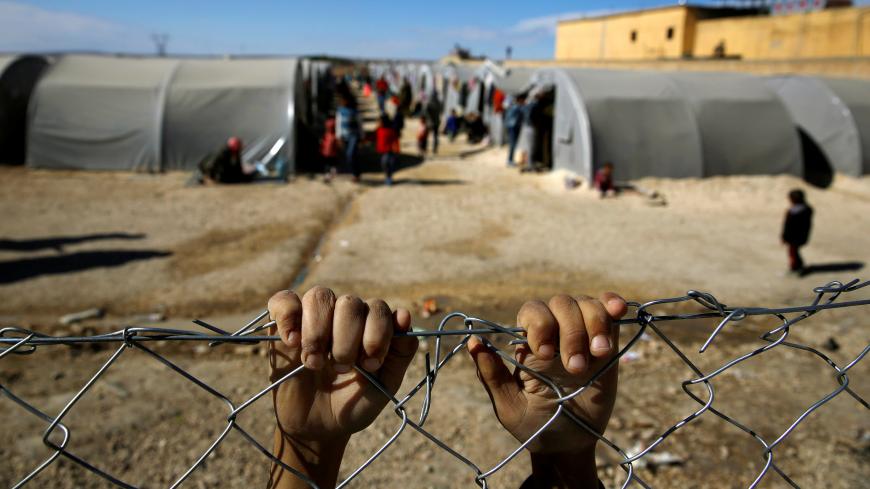 FILE PHOTO: A Kurdish refugee boy from the Syrian town of Kobani holds onto a fence that surrounds a refugee camp in the border town of Suruc, Sanliurfa province, November 3, 2014. REUTERS/Yannis Behrakis/File photo  SEARCH "YANNIS BEHRAKIS" FOR THIS STORY. SEARCH "WIDER IMAGE" FOR ALL STORIES. - RC190D47D5F0