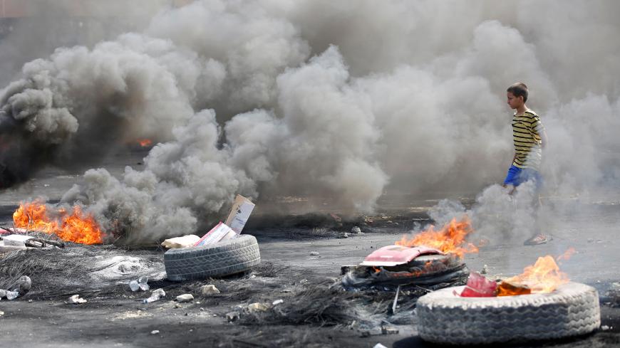 A boy is seen near burning tires during a curfew, two days after the nationwide anti-government protests turned violent, in Baghdad, Iraq October 3, 2019. REUTERS/Wissm al-Okili - RC14A7A0A900