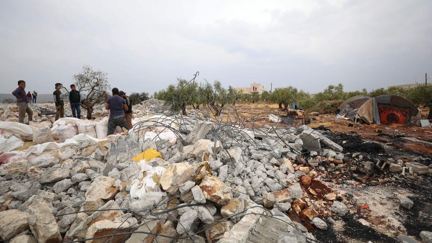A picture taken on October 28, 2019 shows Syrians sifting through the rubble at the site of a suspected US-led operation against Islamic State (IS) chief Abu Bakr al-Baghdadi the previous day, on the edge of the small Syrian village of Barisha in the country's opposition-held northwestern Idlib province. - US President Donald Trump announced that Baghdadi, the elusive leader of the jihadist group and the world's most wanted man, was killed in the early hours of Octobe 27 in an overnight US raid near the vil