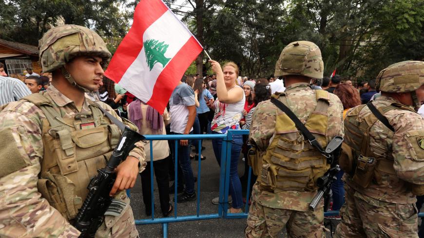 A demonstrator holds a Lebanese flag during an anti-government protest in the southern city of Nabatyeh, Lebanon October 24, 2019. REUTERS/Aziz Taher - RC1B83B80160