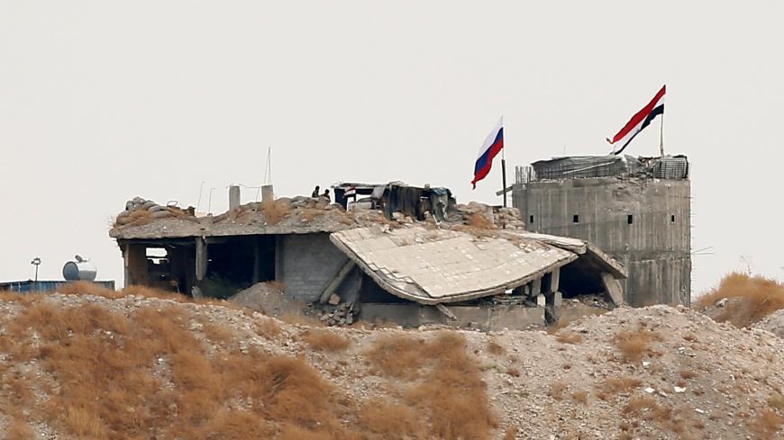 Russian and Syrian national flags are pictured near the northern Syrian village of Zor Magar, as seen from the Turkish border town of Karkamis in Gaziantep province, Turkey, October 23, 2019. REUTERS/Huseyin Aldemir - RC15D8F01E00
