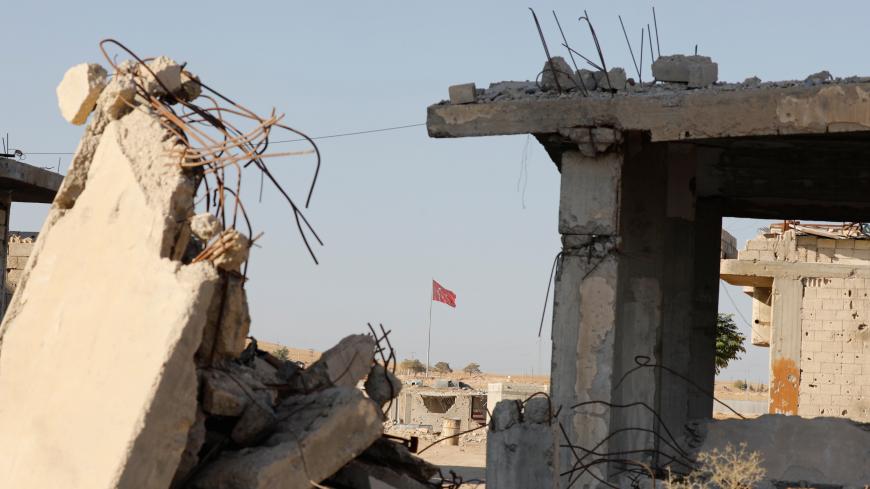 Turkish flag flutters at Turkey's border gate, as pictured on Syria side, overlooking the ruins of buildings destroyed during fightings with the Islamic State militants in Kobani, Syria October 11, 2017. Picture taken October 11, 2017. REUTERS/Erik De Castro - RC1E48BC4870
