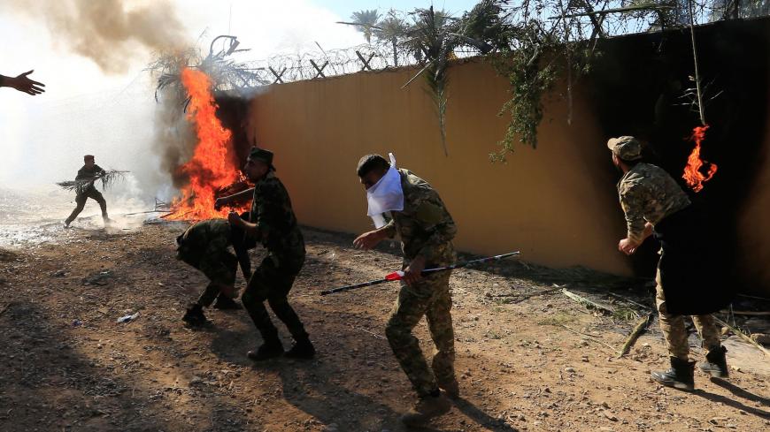 Hashd al-Shaabi (paramilitary forces) fighters set the U.S. Embassy wall on fire as they protest to condemn air strikes on their bases, in Baghdad, Iraq December 31, 2019. REUTERS/Thaier al-Sudani - RC2E6E95X08Z