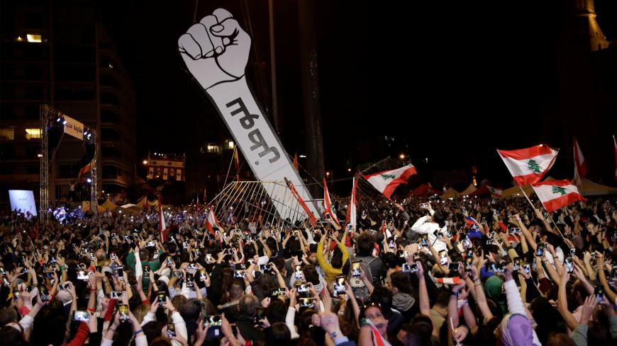 Protesters use their mobile phones as a structure representing a fist is erected to replace a previous one that was burnt at Martyrs' Square in Beirut, Lebanon November 22, 2019. REUTERS/Andres Martinez Casares - RC2JGD9MQQHD
