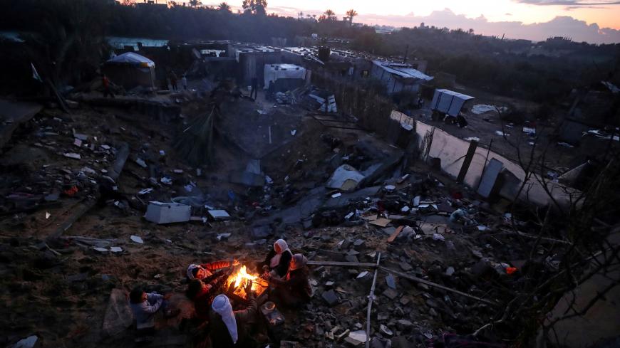 Members of a Palestinian family sit around a fire to warm themselves at the site of their destroyed house, on a rainy day in the southern Gaza Strip January 10, 2020. REUTERS/Mohammed Salem     TPX IMAGES OF THE DAY - RC24DE9KGKN8