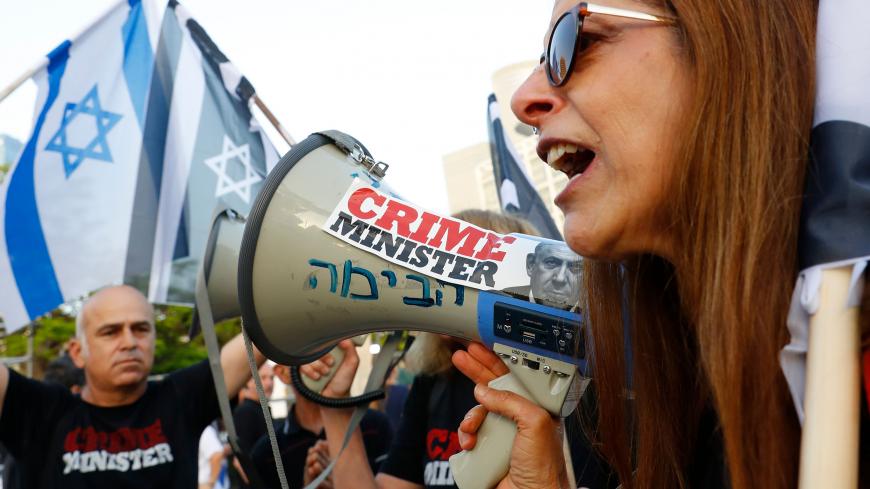 Israeli oposition parties' supporters chant slogans and hold flags as they attend a rally against Prime Minister Benjamin Netanyahu on May 25, 2019 in the coastal city of Tel Aviv. - Israel's attorney general on May 22 extended until October the deadline for Prime Minister Benjamin Netanyahu's pre-trial hearing on corruption allegations, but rejected a request for a 12-month delay. (Photo by JACK GUEZ / AFP) (Photo credit should read JACK GUEZ/AFP via Getty Images)