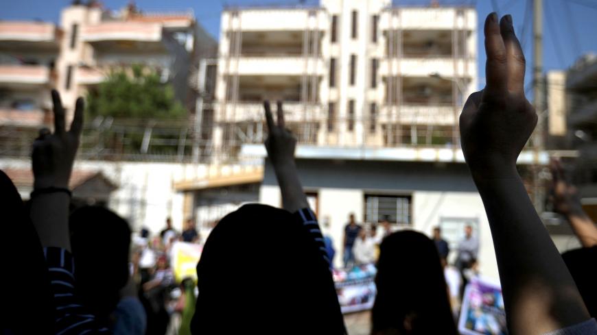 Kurdish and Arab protesters flash the victory sign and chants slogans against Turkish President Tayip Erdogan during a protest in front of the United Nations Headquarters in the town of Qamishli, Syria October 23, 2019. REUTERS/Muhammad Hamed - RC1B8D106F20