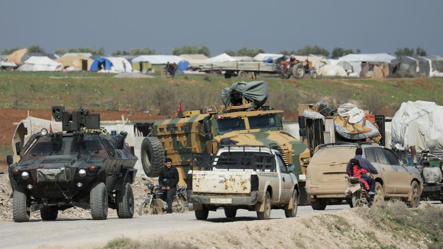 Internally displaced people ride with pick up trucks near Turkish military vehicles in Afrin, Syria February 18, 2020. REUTERS/Khalil Ashawi - RC263F9LKLHP