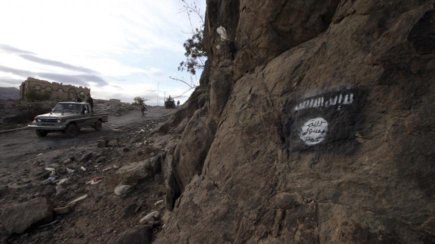 Shi'ite Houthi rebels drive a patrol truck past an Ansar al-Sharia flag painted on the side of a hill, along a road in Almnash, the main stronghold of Ansar al-Sharia, the local wing of Al Qaeda in the Arabian Peninsula (AQAP) in Rada, Yemen November 22, 2014.    To match Special Report YEMEN-AQAP/    REUTERS/Mohamed al-Sayaghi - GF10000374961