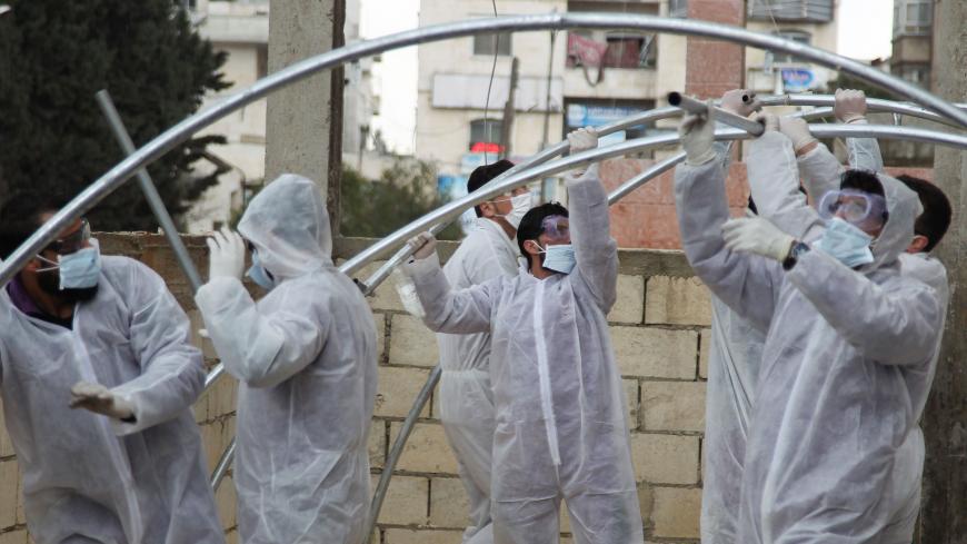 Members of the Syrian Violet NGO set up triage tents for suspected coronavirus patients outside the Ibn Sina Hospital in Syria's northwestern Idlib city on March 19, 2020. - Syrian authorities on March 13 announced measures aimed at preventing coronavirus from reaching the war-torn country, including school closures and a ban on smoking shisha in cafes, state media reported. (Photo by Abdulaziz KETAZ / AFP) (Photo by ABDULAZIZ KETAZ/AFP via Getty Images)