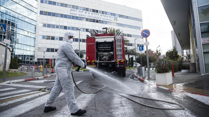 TEL AVIV, ISRAEL - MARCH 20: An Israeli Fire Department crew man sprays disinfectants as he sanitize the entrance to Tel Aviv's Hospital children department on March 20, 2020 in Tel Aviv, Israel. Number of coronavirus in Israel continues to jump, after over 200 new cases have been diagnosed with COVID-19 in the past 24 hours. (Photo by Amir Levy/Getty Images)