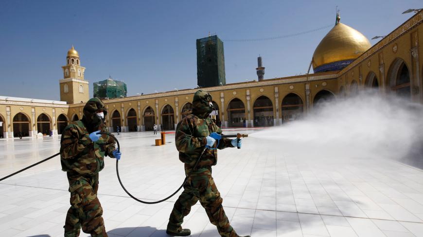 Members of the civil defense team spray disinfectant to sanitize surrounding of the Kufa mosque, following an outbreak of the coronavirus, in the holy city of Najaf, Iraq February 27, 2020. Picture taken February 27, 2020. REUTERS/Alaa al-Marjani - RC2RDF9QBKYW