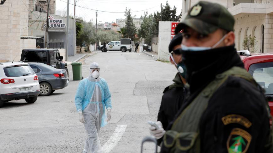 A man in a protective suit walks outside Angel Hotel where, according to a Palestinian government official, a group of American visitors have been quarantined as part of precautions against the coronavirus, in Beit Jala town in the Israeli-occupied West Bank March 7, 2020. REUTERS/Mussa Qawasma - RC2YEF9MKRM8